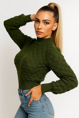 Women's dark green knit sweater with bubble texture and fitted hem, paired with denim jeans